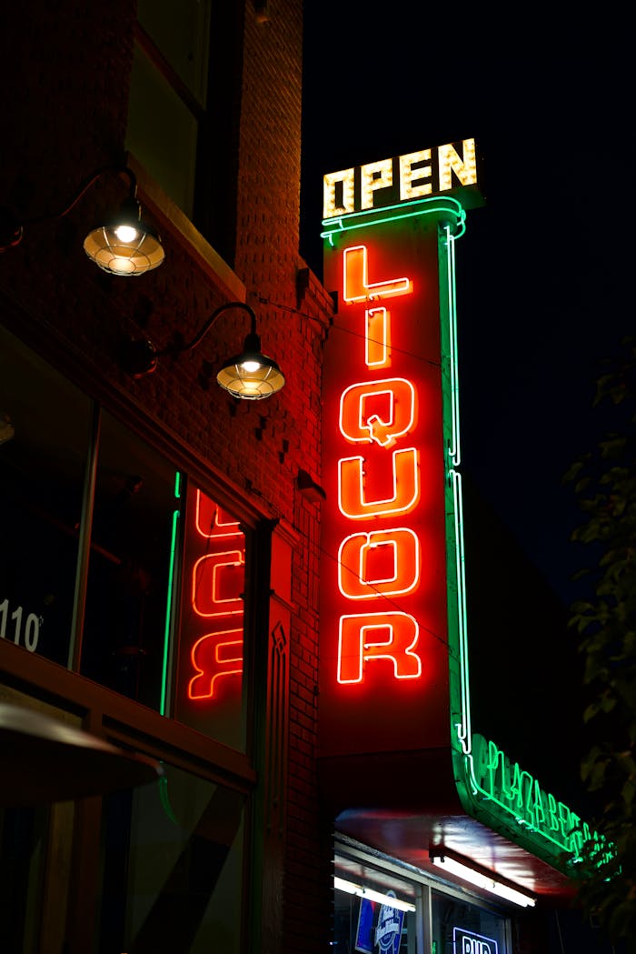 Bright neon liquor store sign glowing against the night sky.